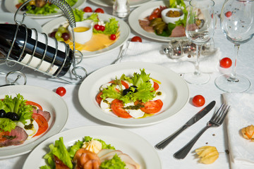 A restaurant dish of curd cheese with tomatoes and olives on a table in a plate. Cold appetizer.
