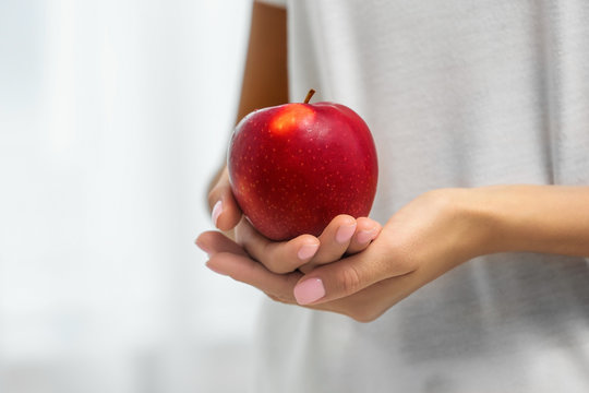 Woman holding fresh red apple on light background, closeup. Space for text