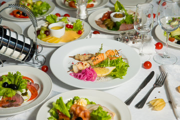 Skewers of fish with a slice of lemon in a plate on a table in the interiors of the restaurant. Cold appetizer.