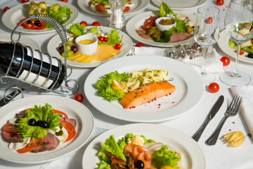 A dish of salmon and boiled potatoes in a plate on the table. Hot restaurant dish.