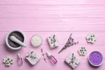 Flat lay composition with hand made soap bars and lavender flowers on pink wooden table, space for text