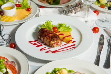 Fried meat patty with baked potato with sauce in a plate on a table. Hot restaurant dish.