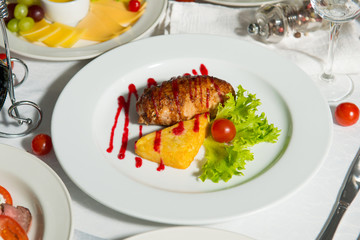 Fried meat patty with baked potato with sauce in a plate on a table. Hot restaurant dish.