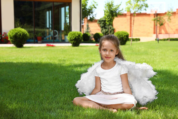 Little girl with angel wings at backyard on sunny day. Space for text