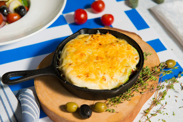 Mushroom julienne with olives on a table against the background of the flag of Greece close-up.