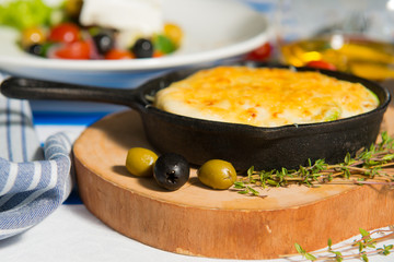 Mushroom julienne with olives on a table against the background of the flag of Greece close-up.