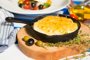 Mushroom julienne with olives on a table against the background of the flag of Greece close-up.