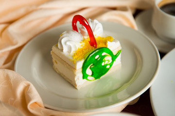 Sponge cake with white cream in a plate in the restaurant's interiors.