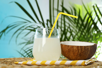 Composition with glass of coconut water on wicker table against blue background