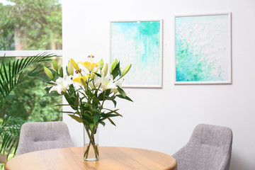 Vase with bouquet of beautiful lilies on wooden table indoors. Space for text