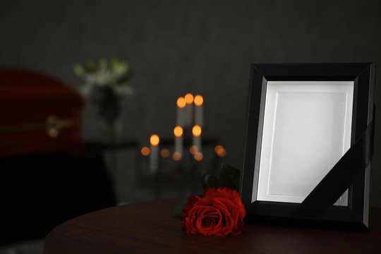 Black photo frame and red rose on table in funeral home