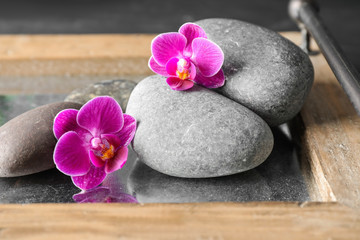Fototapeta na wymiar Composition with orchid flowers and spa stones on tray