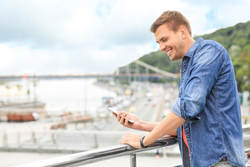 Portrait of handsome man with smartphone on bridge