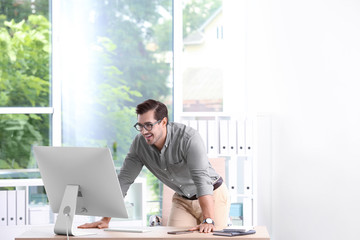 Fototapeta premium Handsome young man working with computer in office