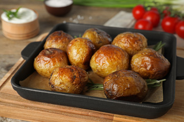 Delicious hot baked potato with sour cream on wooden table