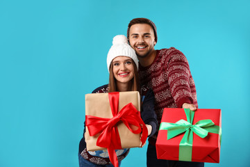Obraz na płótnie Canvas Couple in Christmas sweaters with gift boxes on blue background