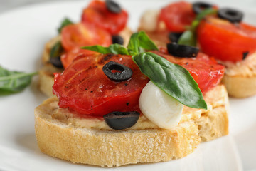 Delicious tomato bruschettas on white plate, closeup