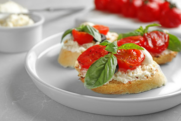 Plate of delicious tomato bruschettas on light grey marble table, closeup