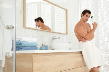 Obraz na płótnie Canvas Handsome young man with deodorant in bathroom