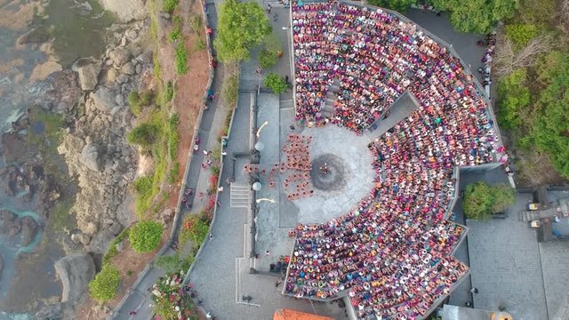 Aerial of Shirtless hindu Men arrive on stage to perform the Dance Kecak In Front Of Tourism. Bali. 4K shot
