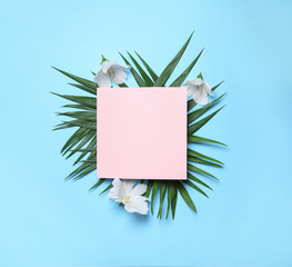 Flat lay composition with tropical leaves and Hibiscus flowers on blue background. Space for text