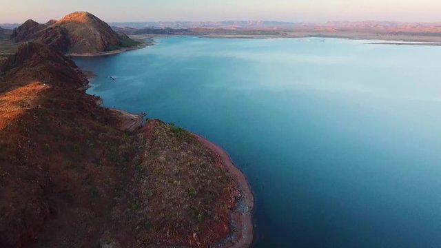 Aerial shot of drone moving forward while tilting up to reveal spectacular lake argyle and surrounding mountains.