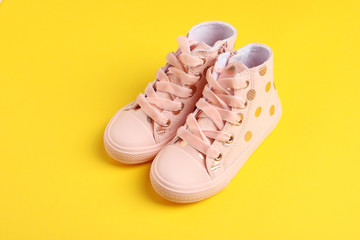Pair of stylish child shoes on yellow background