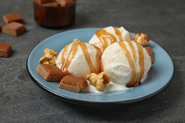 Delicious ice cream with caramel topping on grey table