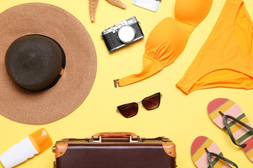 Flat lay composition with suitcase and beach objects on yellow background
