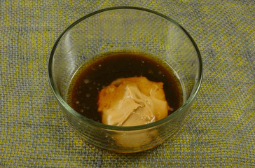 Making sauce with peanut butter with soy sauce, sesame oil, and ginger juice in glass mixing bowl