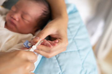 Asian baby getting fingernails cut.