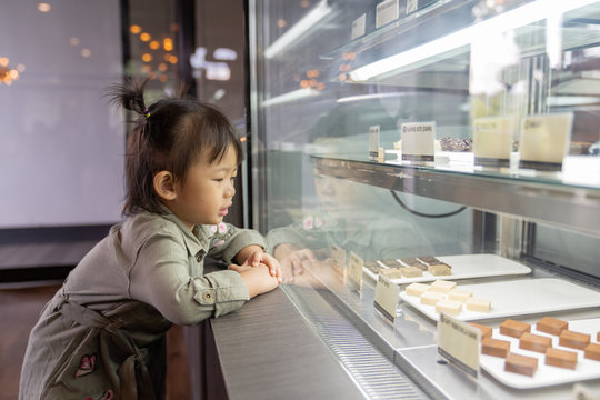 Asian cute little girl looking excited in bakery counter.