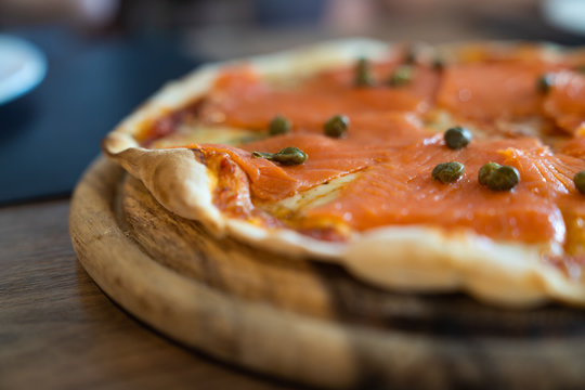 Full delicious fresh salmon pizzas on wood table.
