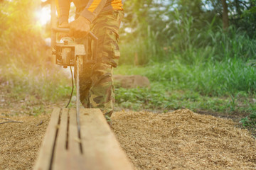 Lumberjack. woodcutter sawing chain saw in motion, sawdust fly to sides.