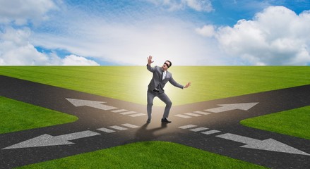 Young businessman at crossroads in uncertainty concept