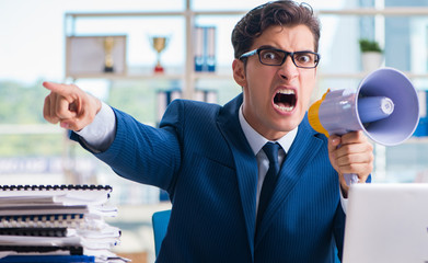Angry aggressive businessman with bullhorn loudspeaker in office