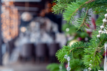 Christmas interior veranda modern restaurant setting, serving banquet, gray textile chairs, serving tables, wine glasses, plates, cutlery and fir branches. Concept new year decoration