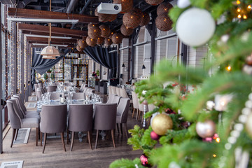 Christmas interior veranda modern restaurant setting, serving banquet, gray textile chairs, serving tables, wine glasses, plates, cutlery and fir branches. Concept new year decoration