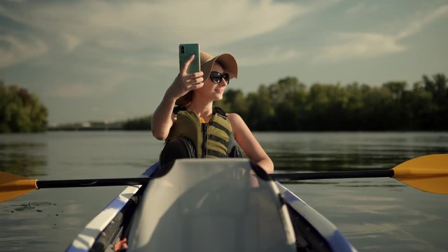Selfie On Mobile Phone In Beautiful Place On Tranquil Water Pond At Sunset Time.Woman Taking Selfie On A Kayak Boat On Evening.Girl Making Self Photo And Answer To Video Call.