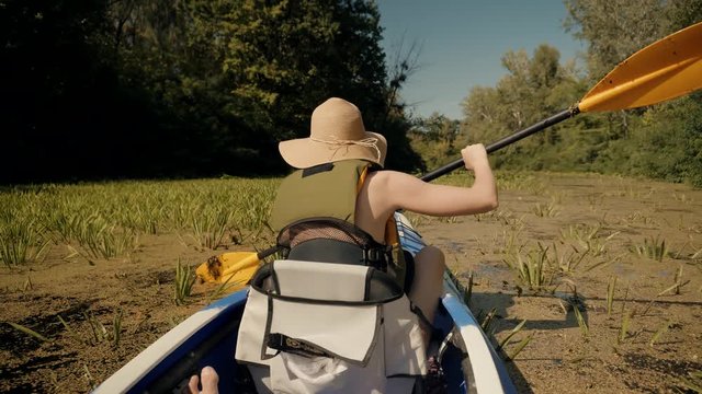 Girl In Kayak.Girl Traveller In Life Vest Swims In Kayak Boat In Tranquil Pond.Woman Exploring Calm River By Canoe.Pretty Woman In Hat And Sunglasses Kayaking On Lake At Sunset And Holds Oar Close Up 