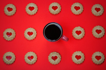 Heart shaped red jam filled cookies and a cup of coffee with laptop on red background.Valentines day concept