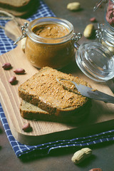 Homemade Organic Creamy Peanut Butter in a jar ,Peanut Butter toast with Knife on Wooden Surface andpeanuts around on dark grunge background,toned photo,selective focus