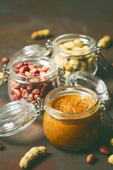 Homemade Organic Creamy Peanut Butter in a jar ,Peanut Butter toast with Knife on Wooden Surface andpeanuts around on dark grunge background,toned photo,selective focus