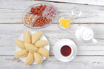 Traditional Azerbaijan holiday Novruz cookies baklava on white plate on the white background with nuts and shakarbura,tea,lemon,kata,mutaki,flat lay,top view,space for copy