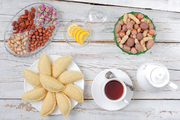 Fototapeta na wymiar Traditional Azerbaijan holiday Novruz cookies baklava on white plate on the white background with nuts and shakarbura,tea,lemon,kata,mutaki,flat lay,top view,space for copy