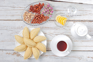 Traditional Azerbaijan holiday Novruz cookies baklava on white plate on the white background with nuts and shakarbura,tea,lemon,kata,mutaki,flat lay,top view,space for copy