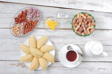 Traditional Azerbaijan holiday Novruz cookies baklava on white plate on the white background with nuts and shakarbura,tea,lemon,kata,mutaki,flat lay,top view,space for copy