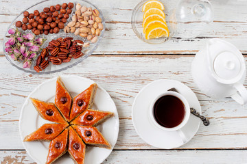 Traditional Azerbaijan holiday Novruz cookies baklava on white plate on the white background with nuts and shakarbura,tea,lemon,kata,mutaki,flat lay,top view,space for copy
