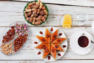 Traditional Azerbaijan holiday Novruz cookies baklava on white plate on the white background with nuts and shakarbura,tea,lemon,kata,mutaki,flat lay,top view,space for copy