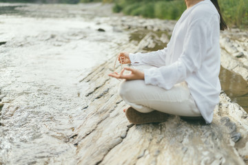peaceful woman is making mantra meditation near river
